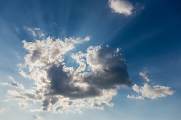 Fototapeta na wymiar Sun beams from behind of cumulus cloud on a sky