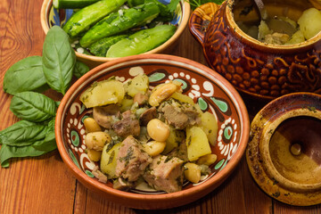 Meat stewed with vegetables in clay pot on rustic table