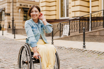 Brunette woman sitting in wheelchair on city street