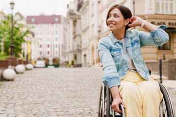 Obraz premium Brunette woman sitting in wheelchair on city street