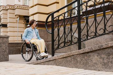 Mid aged brunette disabled woman sitting in a wheelchair - obrazy, fototapety, plakaty