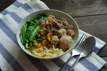 a bowl of meatball soup with vegetables in a wooden background 