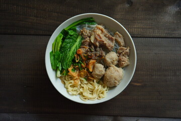 a bowl of meatball soup with vegetables in a wooden background 