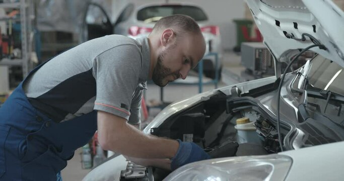 Professional mechanic testing a car battery with a tester