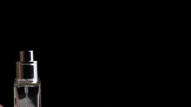 The man's hand presses on the perfume diffuser on a black background. Copy space for text, close-up, aroma