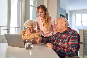Curious senior couple with daughter on laptop computer