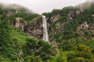 Beautiful mountain waterfall among trees, summer natural background