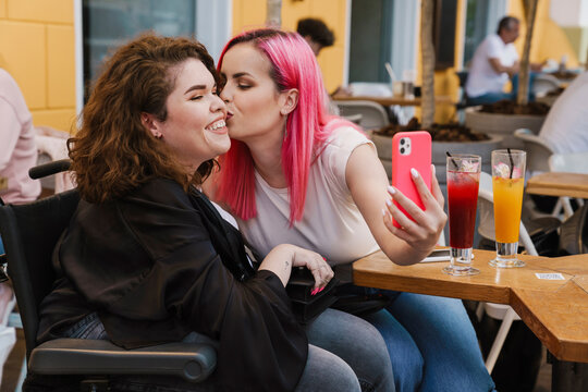 Young two women smiling and drinking Young three women taking selfie on cellphone while sitting in cafe while sitting in cafe
