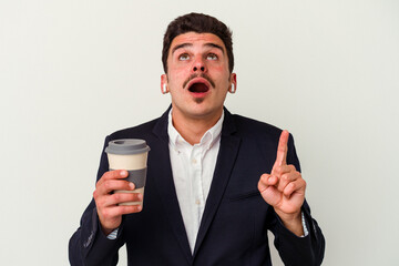 Young business caucasian man wearing wireless headphones and holding take way coffee isolated on white background pointing upside with opened mouth.