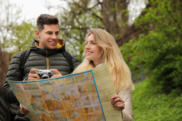 Fototapeta na wymiar Couple of tourists with map planning trip in park