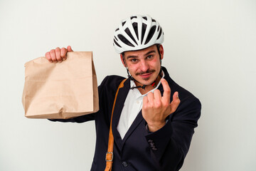 Young business caucasian man wearing bike helmet and holding take way food isolated on white background pointing with finger at you as if inviting come closer.