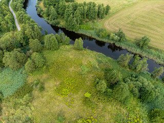 Aerial, drone photography of river, green fields, trees and a path. Photography taken in Sweden in summer time. Copy space and place for text.