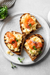 Scrambled egg sandwich with salmon on a ceramic plate on a white background, selective focus, top view