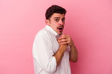 Young caucasian man isolated on pink background scared and afraid.