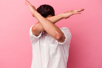 Young caucasian man isolated on pink background keeping two arms crossed, denial concept.