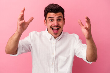 Fototapeta premium Young caucasian man isolated on pink background receiving a pleasant surprise, excited and raising hands.