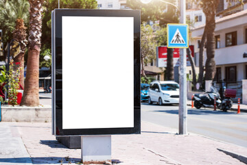 White advertising lightbox in black frame stands vertically on sidewalk