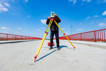 Civil engineer, geodesist is working with total station on a building site, unfinished bridge