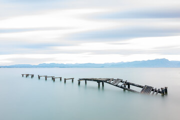 Fototapeta premium Abandoned wooden pier in lake during sunrise, long exposure