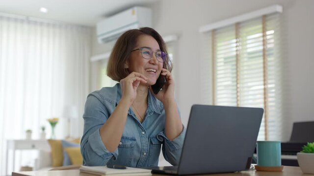 Asia healthy elder people, SME owner lady or latin telesale service agent manager answer cellphone call via 5G wifi wireless relax sit at home office desk with smile humor laugh client care job.