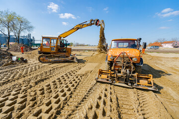 Truck plate compactor and earthmover are working at construction site