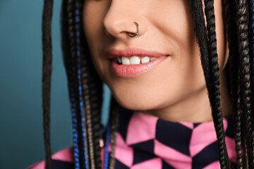 Young woman with nose piercing on light blue background, closeup