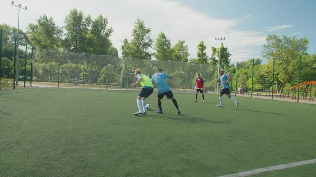 Diverse mixed race soccer players playing on football pitch while defender pushing opponent striker. Sports referee whistling because of foul. Footballers expressing disagreement, arguing with arbiter