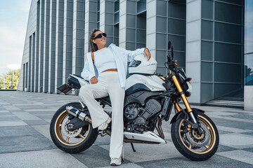 Fototapeta na wymiar Relaxed female biker with her white modern motorcycle