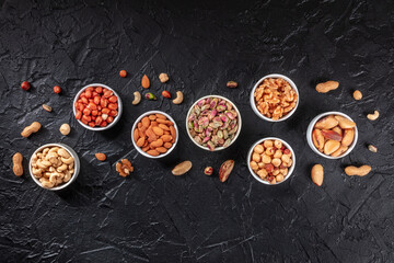 Nuts, overhead flat lay shot on a black slate background with a place for text