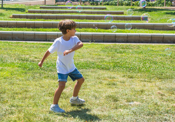 Little Boy Playing In The Park With Soap Bubbles. 6 Year Old Boy Enjoying In The Park On A Sunny Summer Day.