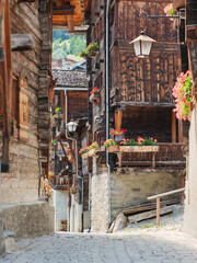 Partial view of beautiful traditional wooden houses, also called Swiss chalet, in a narrow alley in the alpine village of Grimentz, in the canton of Valais (Switzerland), municipality of Anniviers.