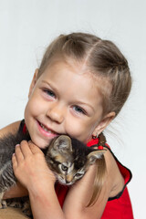 Obraz premium Portrait of cute caucasian girl of five years old holding kitten looking at camera on the white background