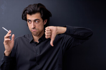 sad young man showing Gesture for anti, quit smoking addiction concept. Stop smoking message, social issue concept, black studio background. no smoking in world concept. male looking at side seriously