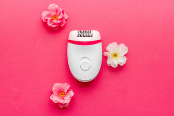 Obraz na płótnie Canvas Epilator with pink and white flowers. Hair removal and depilatory concept