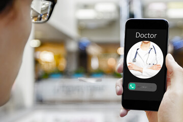 Hand holding mobile phone with incoming call from doctor on blurry interior background. Distant consultation concept.