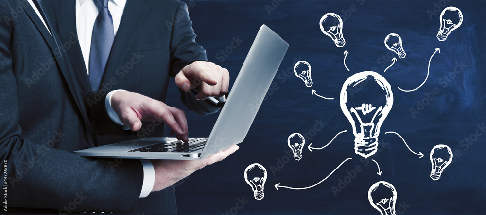 Poster two european businessmen using laptop with abstract light bulb sketch on blackboard wall background.