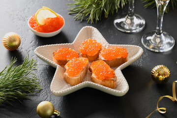 Russian appetizer canape with red caviar on ciabatta on black background for Christmas, New Year...