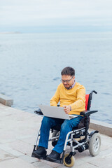 a man with disabilities in a wheelchair works on a computer on the Internet