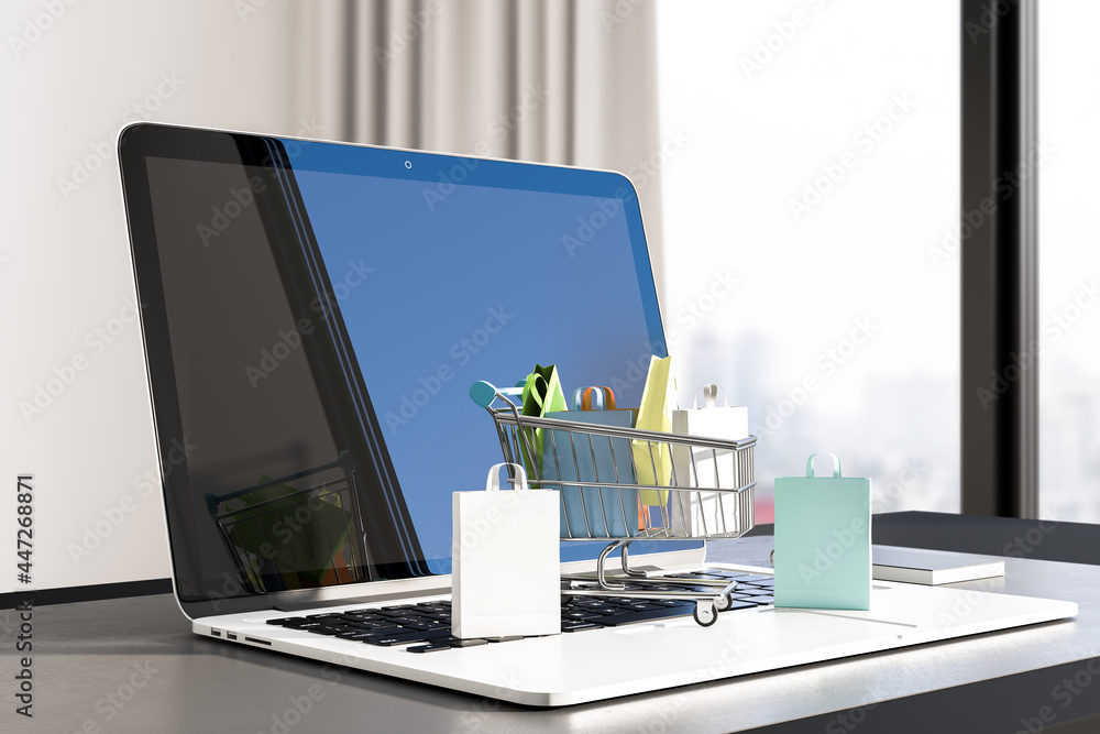 Poster close up of desktop with laptop and tiny shopping carts on keaybord. blurry window with city view ba