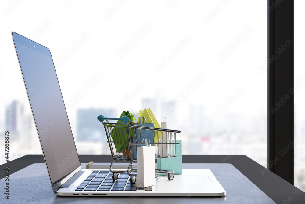 Aufkleber Close up of desk with laptop and tiny shopping carts on keaybord. Blurry window with city view background. Online shopping and commerce concept. 3D Rendering.