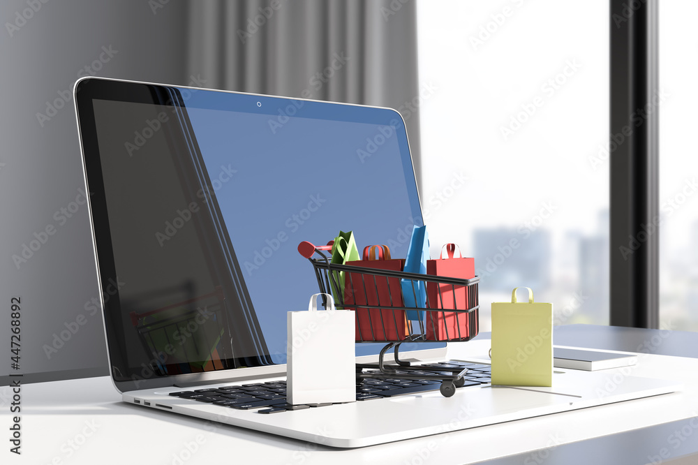 Aufkleber close up of workplace with laptop and tiny shopping carts on keaybord. blurry window with city view 