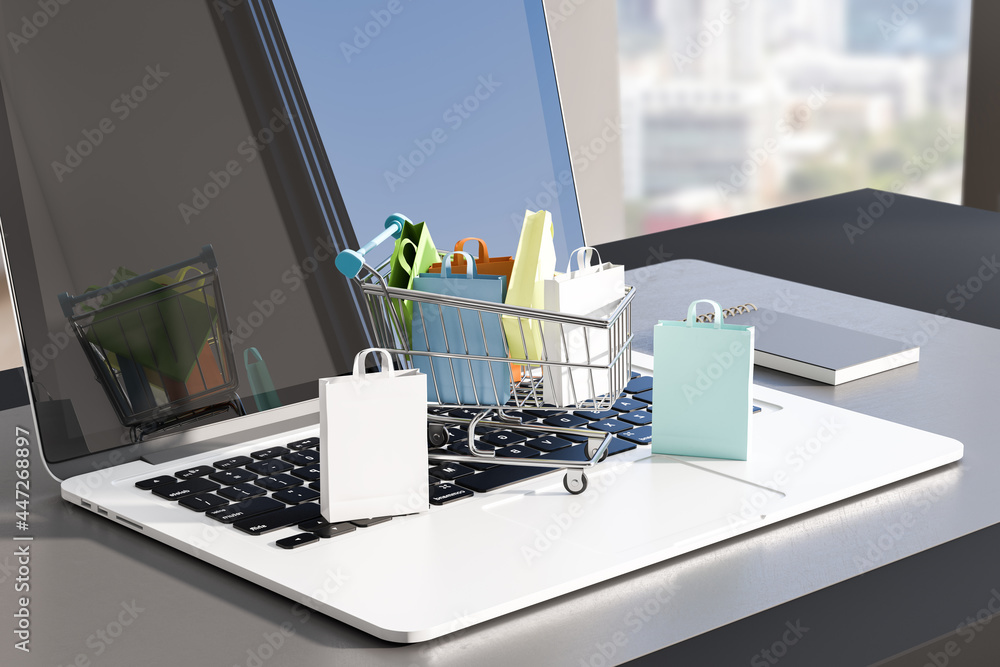 Aufkleber close up of table with laptop and tiny shopping carts on keaybord. blurry window with city view back