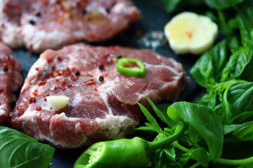 Fototapeta na wymiar Raw meat steaks with spices and basil. Pork steaks.