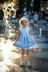 happy little girl running under splashing water