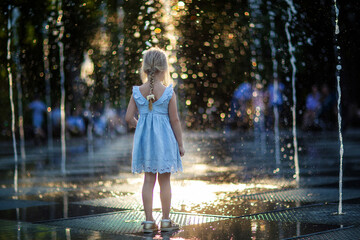 happy little girl running under splashing water