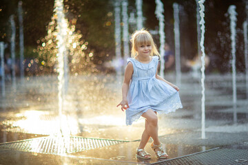 happy little girl running under splashing water