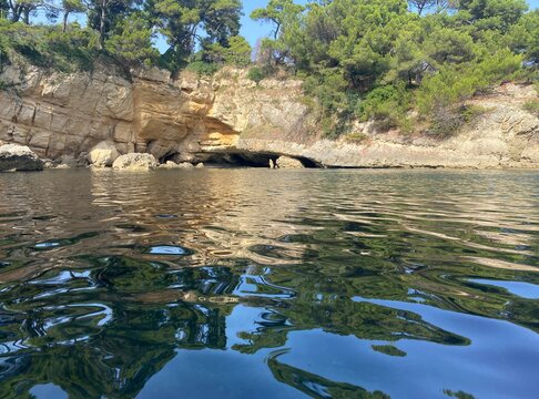 Paradise sea laguna summer landscape. Blue sea waves. Glittering clear water. Mysterious grotto cave in coastal cliff view. Beautiful nature of Mediterranean coast at summertime. Relax. Sun. Seascape.