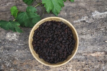 Dried black currant berries and green leaves grapes on wood table  background.