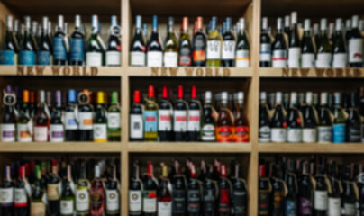 Blurred image of Various wine bottles sale on the wooden shelf in a supermarket shop.