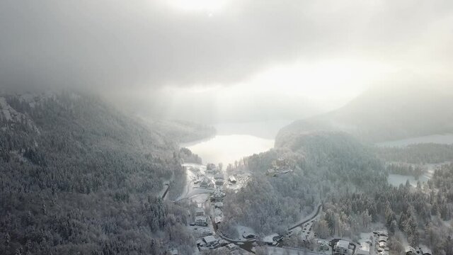 Aerial drone view of castle Neuschwanstein and schwangau in fog during winter in snow and ice in the Alps partly sunny, Germany